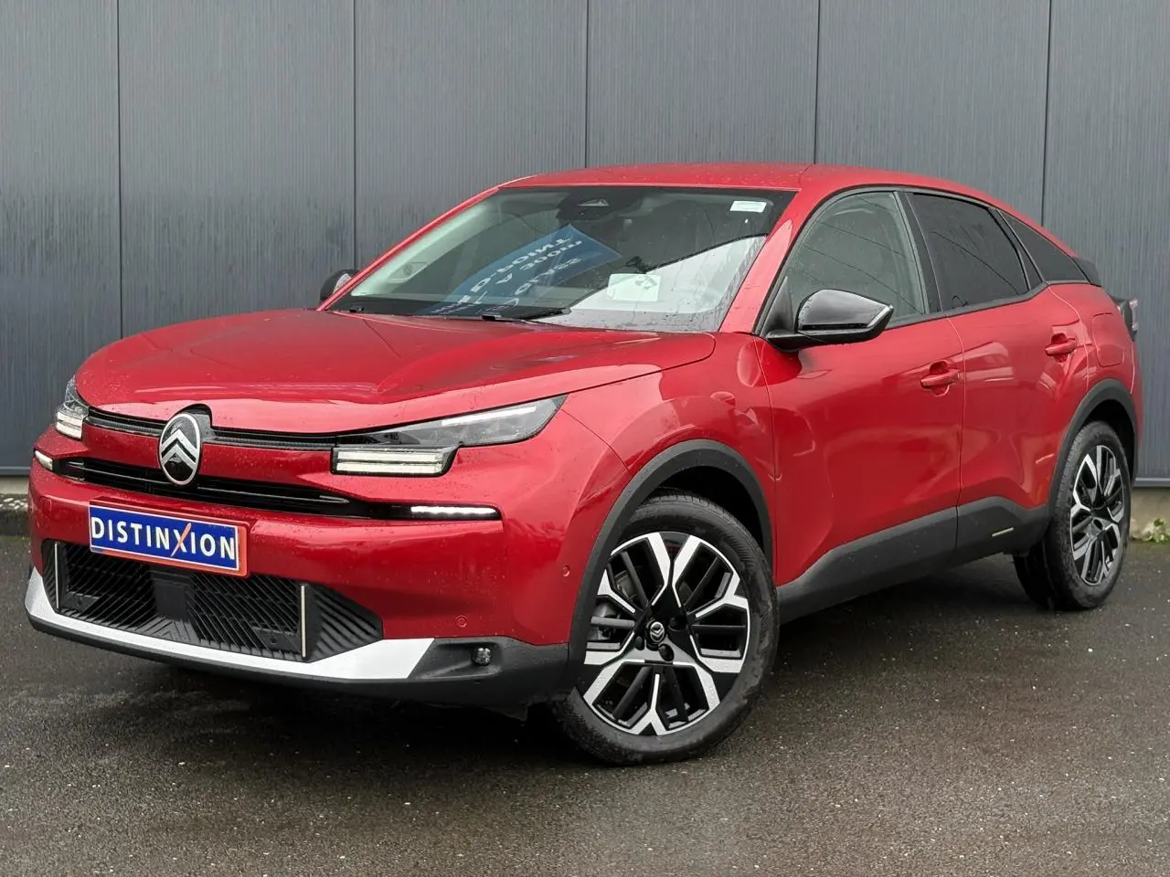 Vue 3/4 avant droite d'une Citroën C4 Hybrid 2025 rouge Elixir avec jantes alliage et phares LED distinctifs.