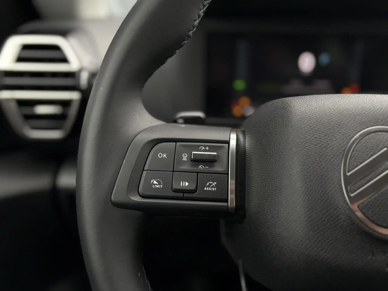Gros plan sur le volant noir de la Citroën C4 Hybrid 2025, avec commandes intégrées côté gauche.