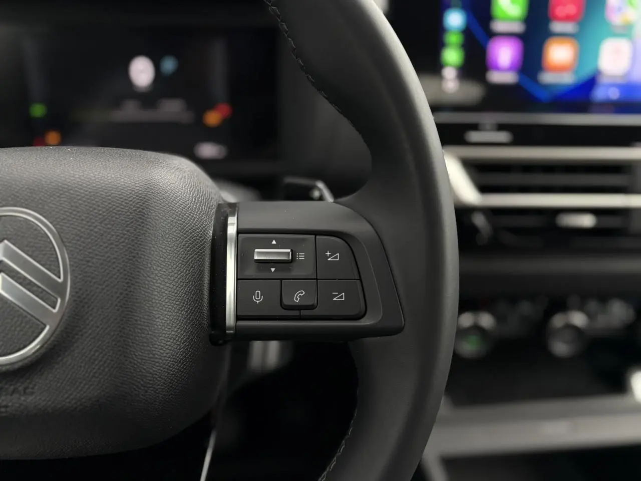 Gros plan sur les commandes au volant cuir noir de la Citroën C4 Hybrid 145, avec écran tactile en arrière-plan.
