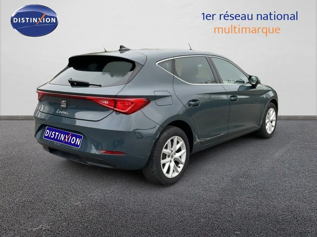 Vue 3/4 arrière droite d'une SEAT Leon gris magnétique métal avec feux arrière distinctifs et jantes argentées.