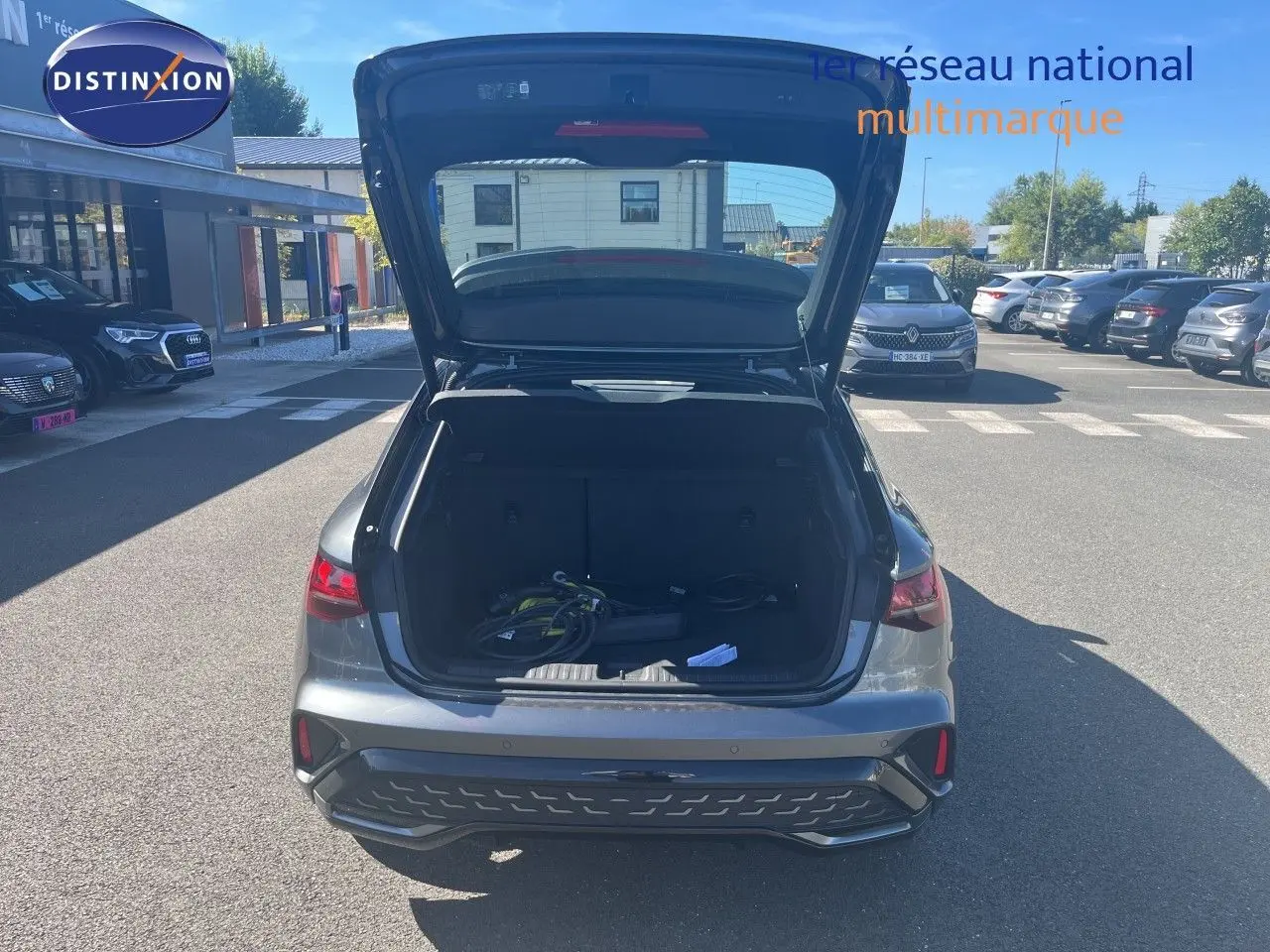 Vue arrière avec coffre ouvert d'une Audi A3 Sportback 40 TFSIe gris Daytona Metal, montrant le volume de chargement et câbles de recharge.