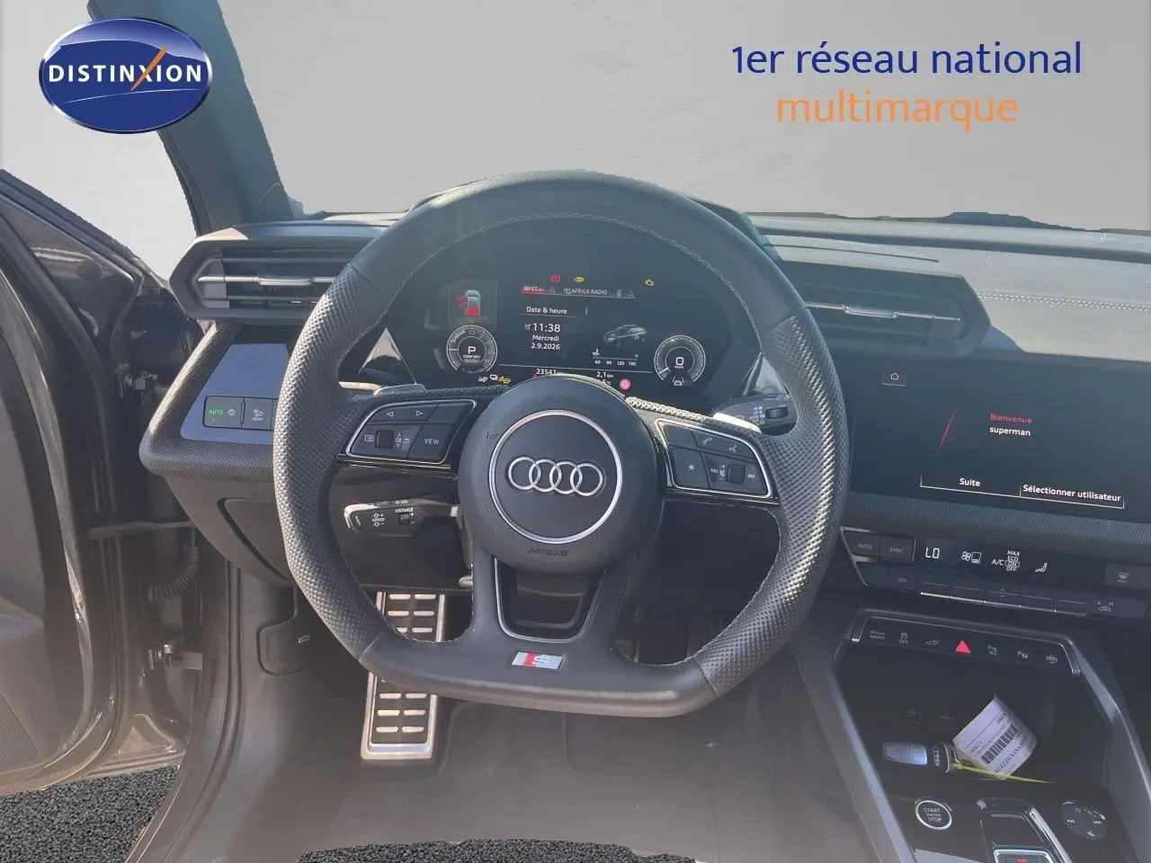 Vue intérieure centrée sur le volant cuir noir perforé et le tableau de bord numérique de l'Audi A3 Sportback 2025.