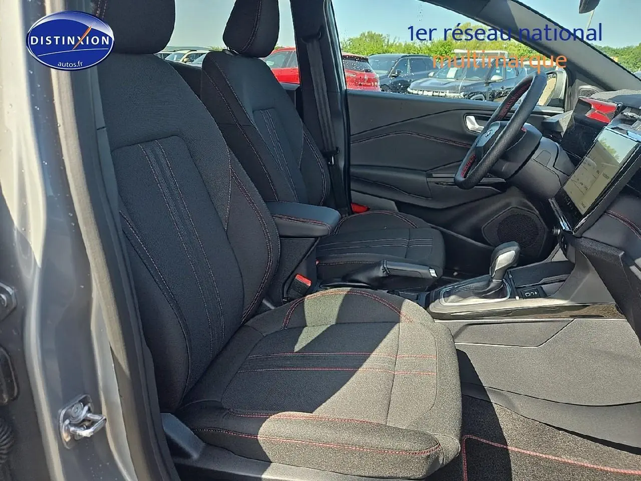 Intérieur avant droit du Ford Puma gris cactus 2025 avec sièges tissu noirs et surpiqûres rouges visibles.