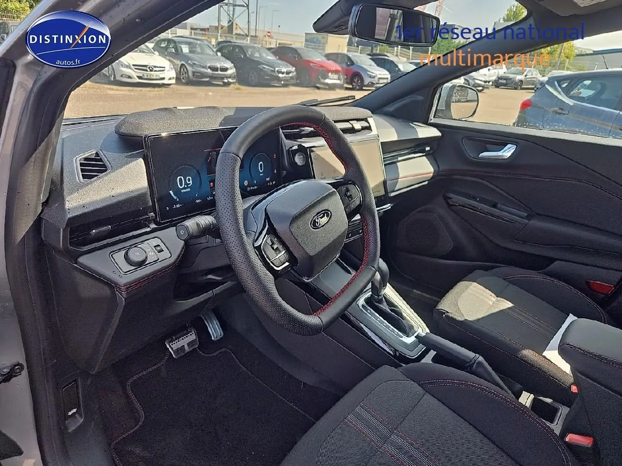 Intérieur côté conducteur du Ford Puma gris cactus 2025, volant cuir avec surpiqûres rouges et écran tactile central.