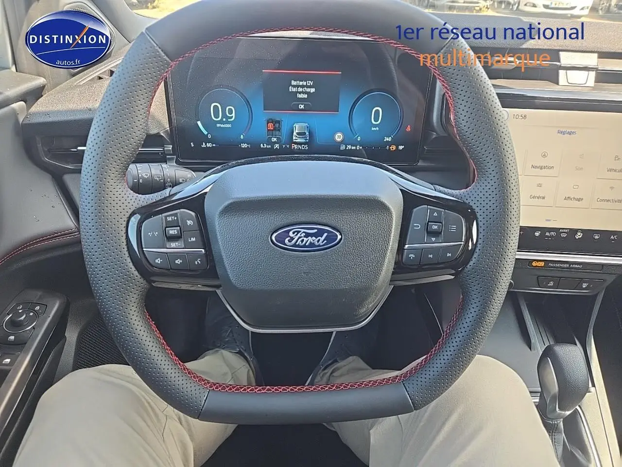 Vue intérieure centrée sur le volant perforé avec surpiqûres rouges et tableau de bord numérique du Ford Puma 2025.