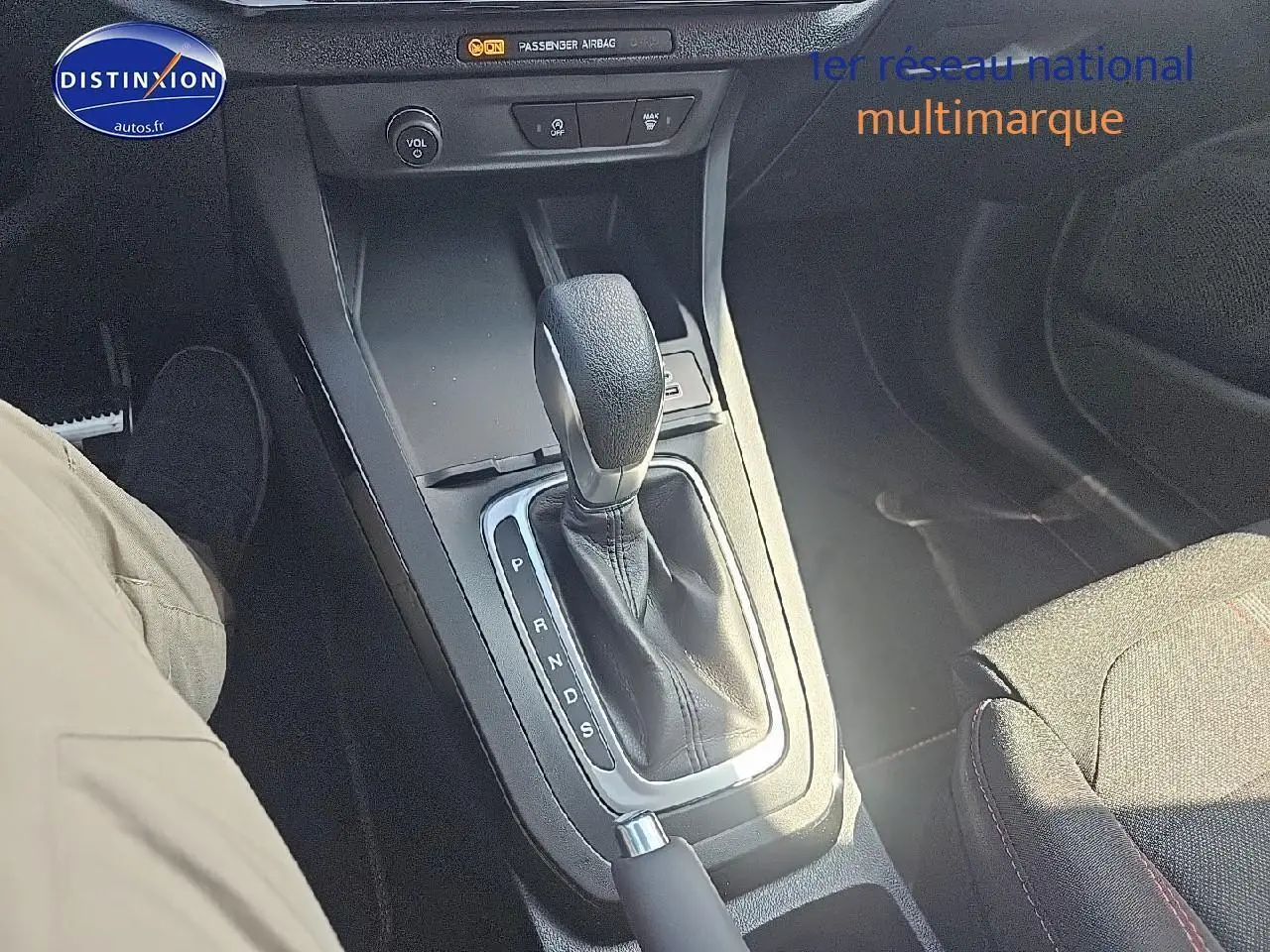 Le levier de boîte automatique au centre de la console d'une Ford Puma 2025, tissu noir avec surpiqûres rouges visible.