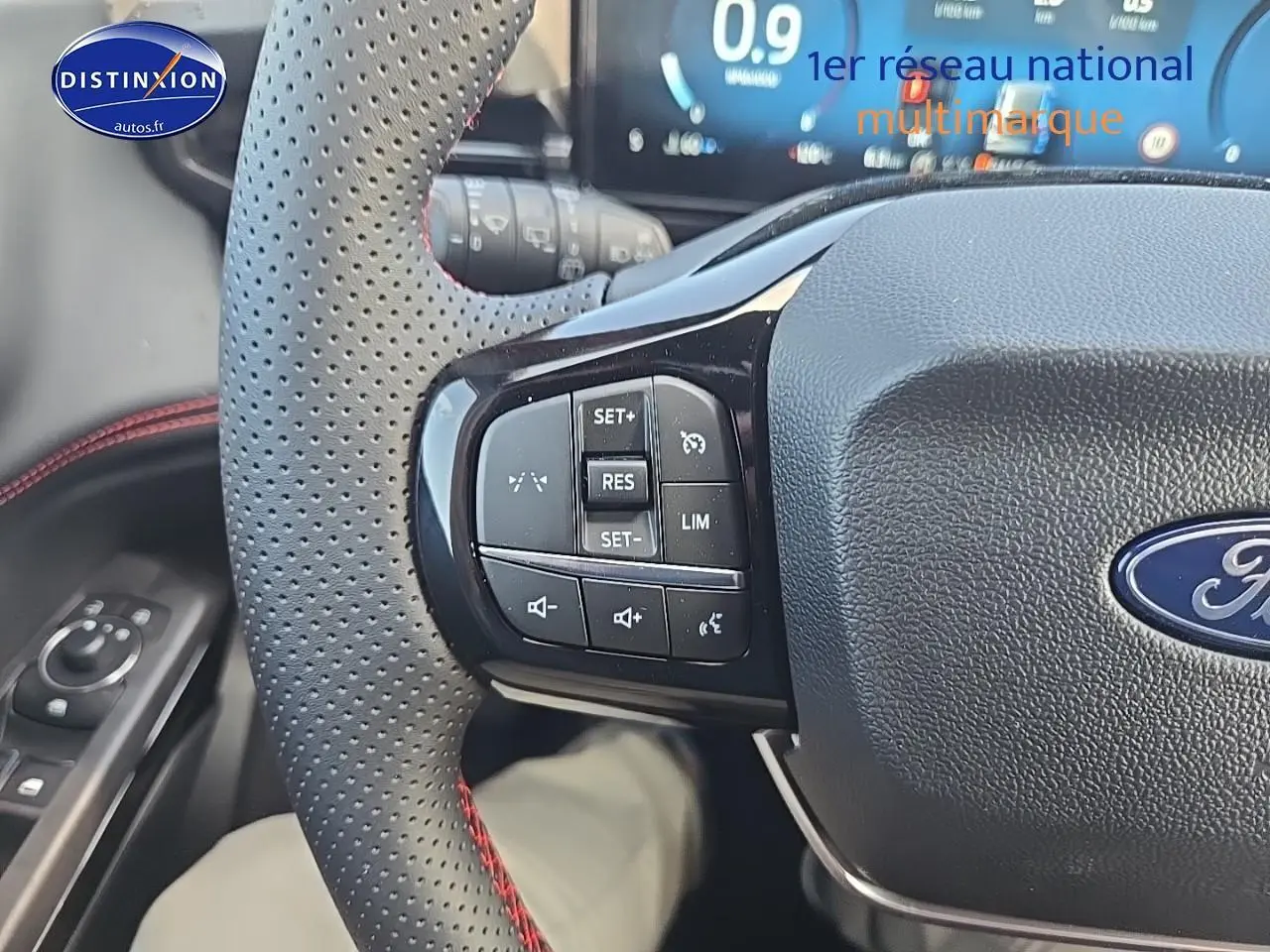Gros plan sur le volant perforé avec surpiqûres rouges du Ford Puma 2025, boutons de régulateur de vitesse visibles.