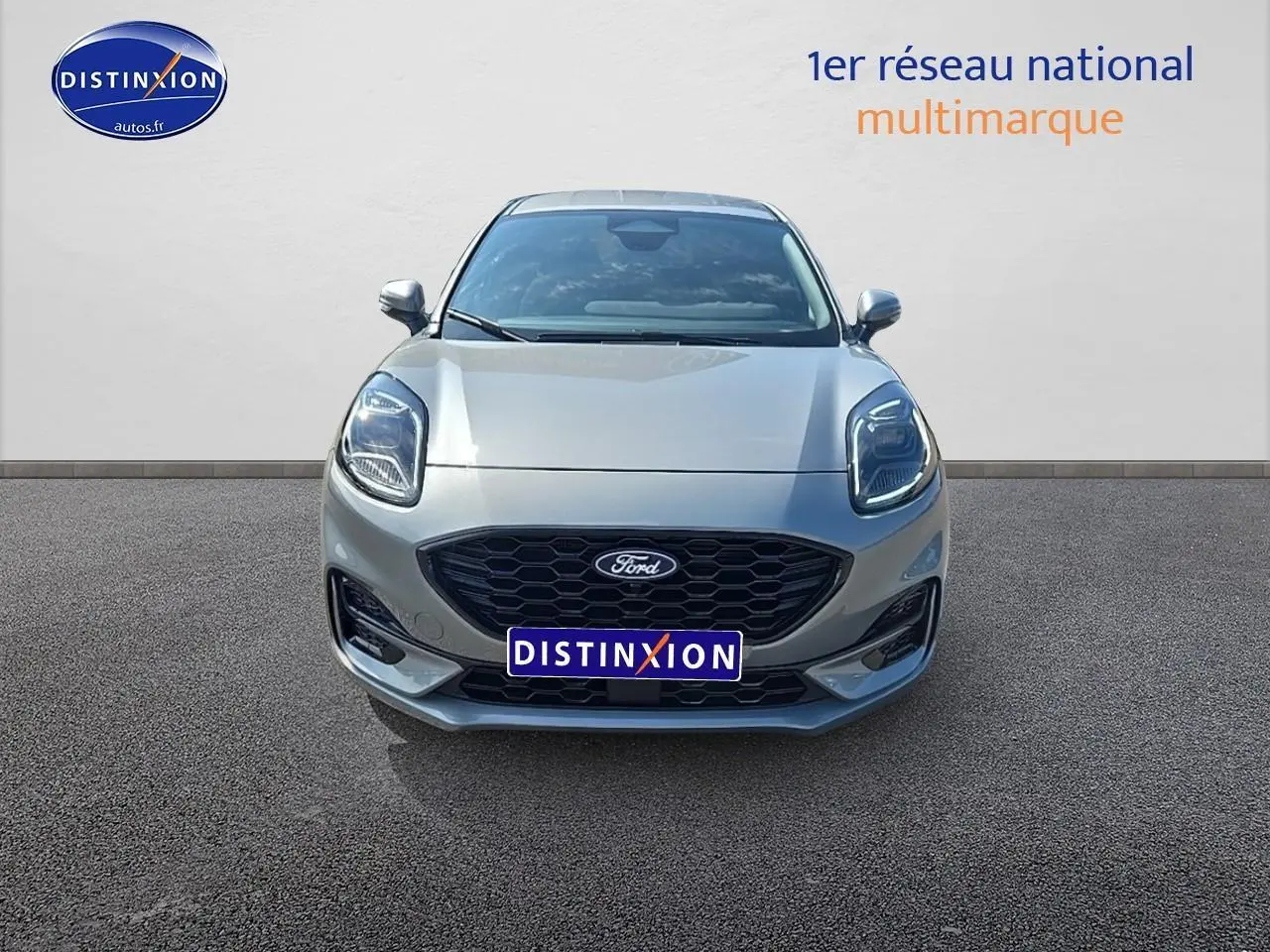 Vue frontale du Ford Puma 2025 gris cactus avec calandre noire et phares LED allumés sur fond neutre.
