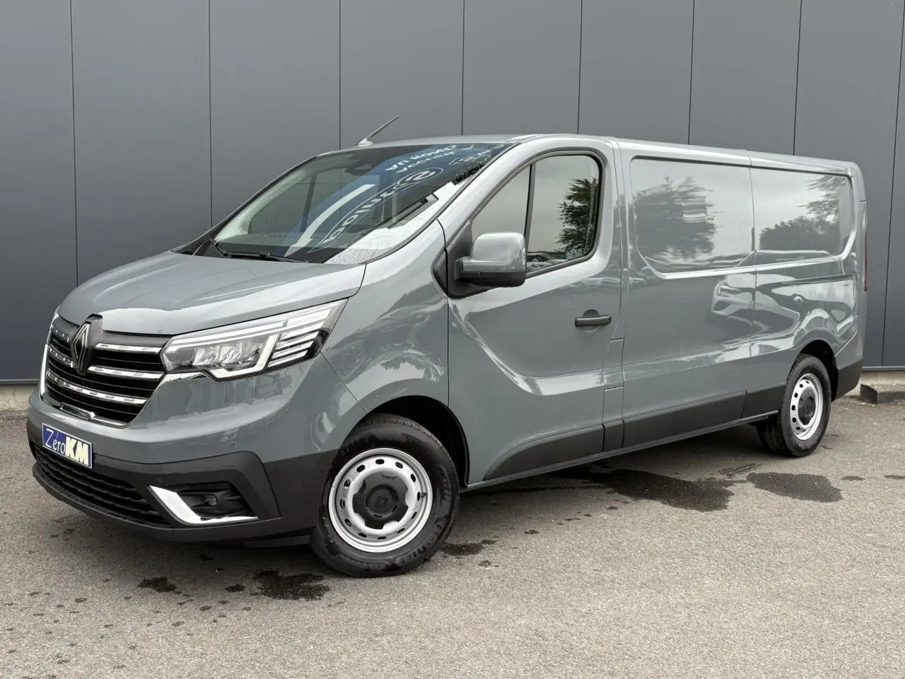 Renault Trafic Fourgon gris urbain en 3/4 avant droit, avec projecteurs Full LED et jantes acier simples.