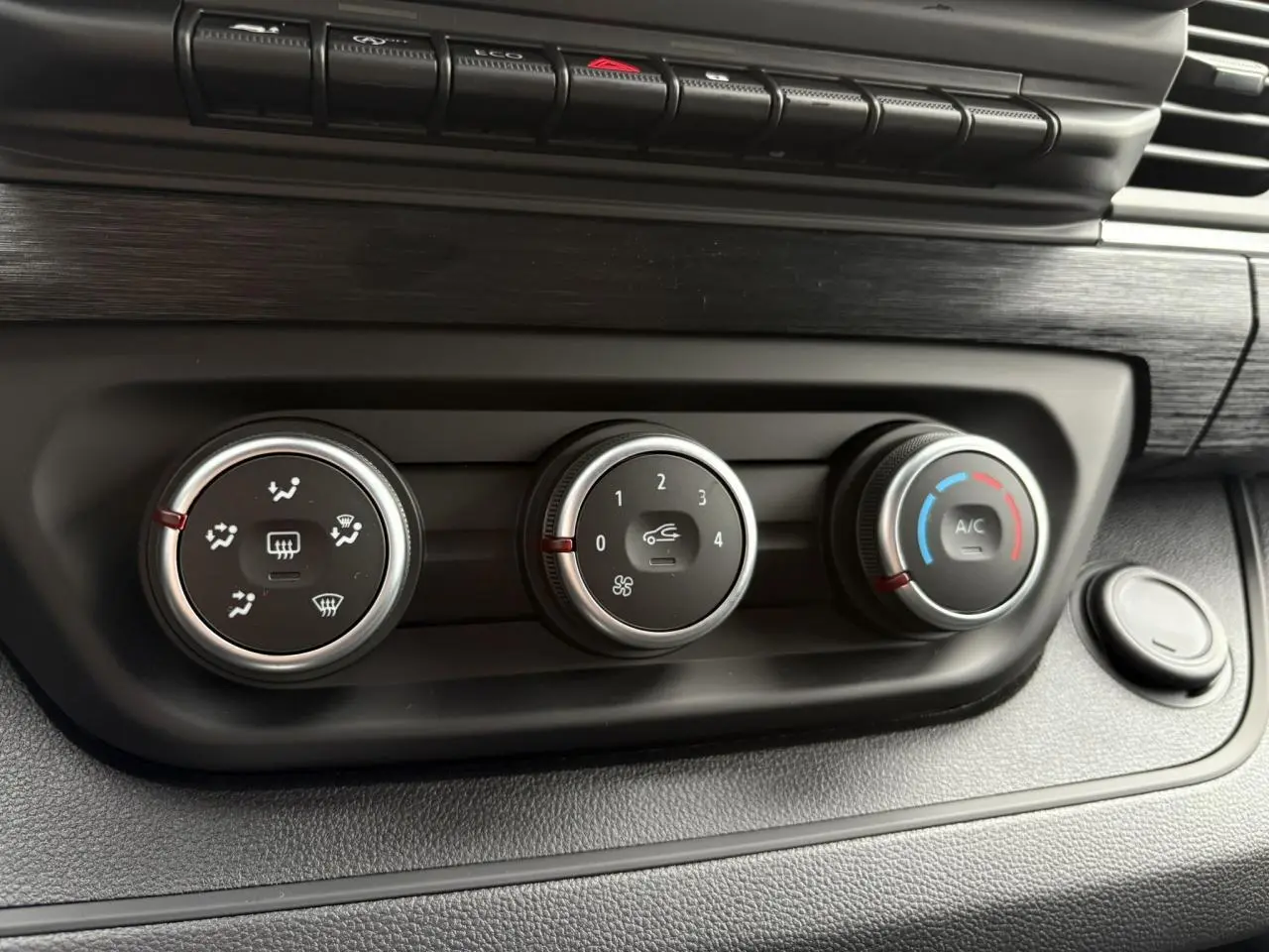 Gros plan sur les commandes de climatisation du tableau de bord noir du Renault Trafic Fourgon Gris Urbain 2025.