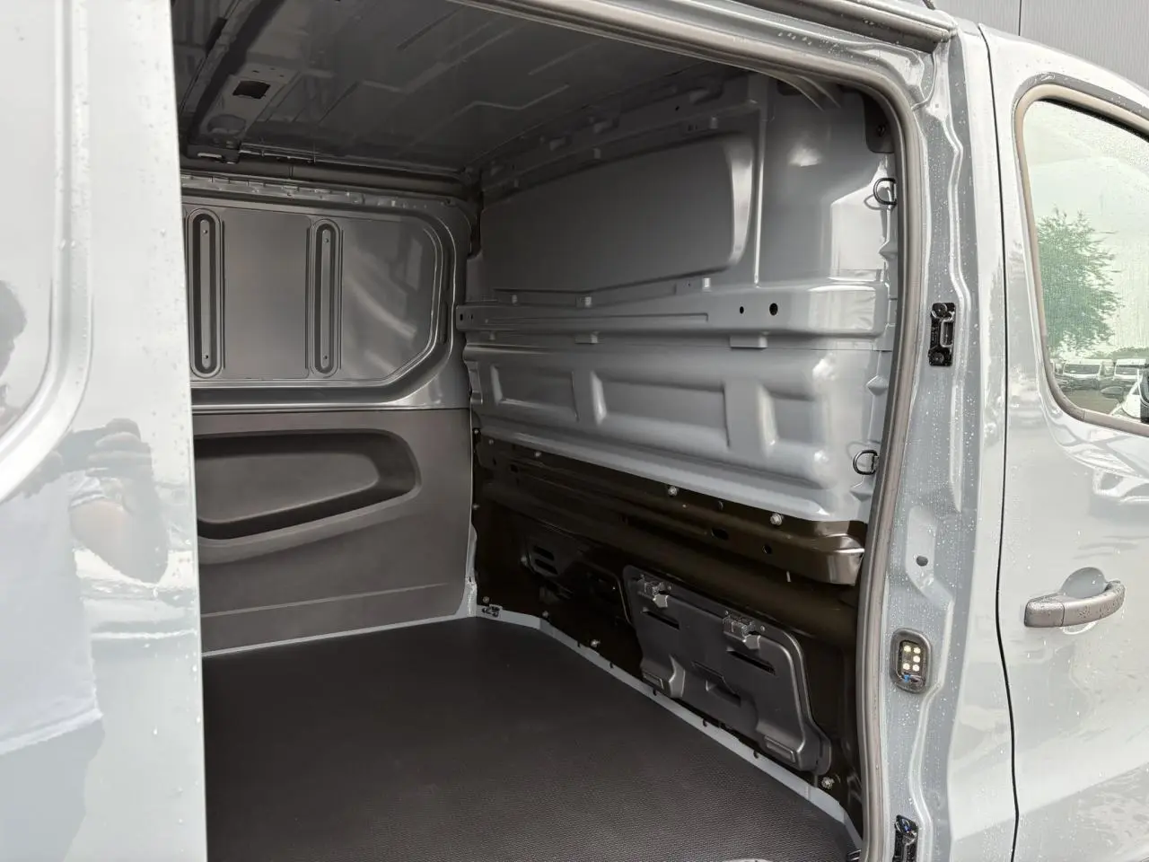 Intérieur du fourgon Renault Trafic L2H1 2025 en Gris Urbain, vue côté droit avec plancher antidérapant et cloison tôlée.