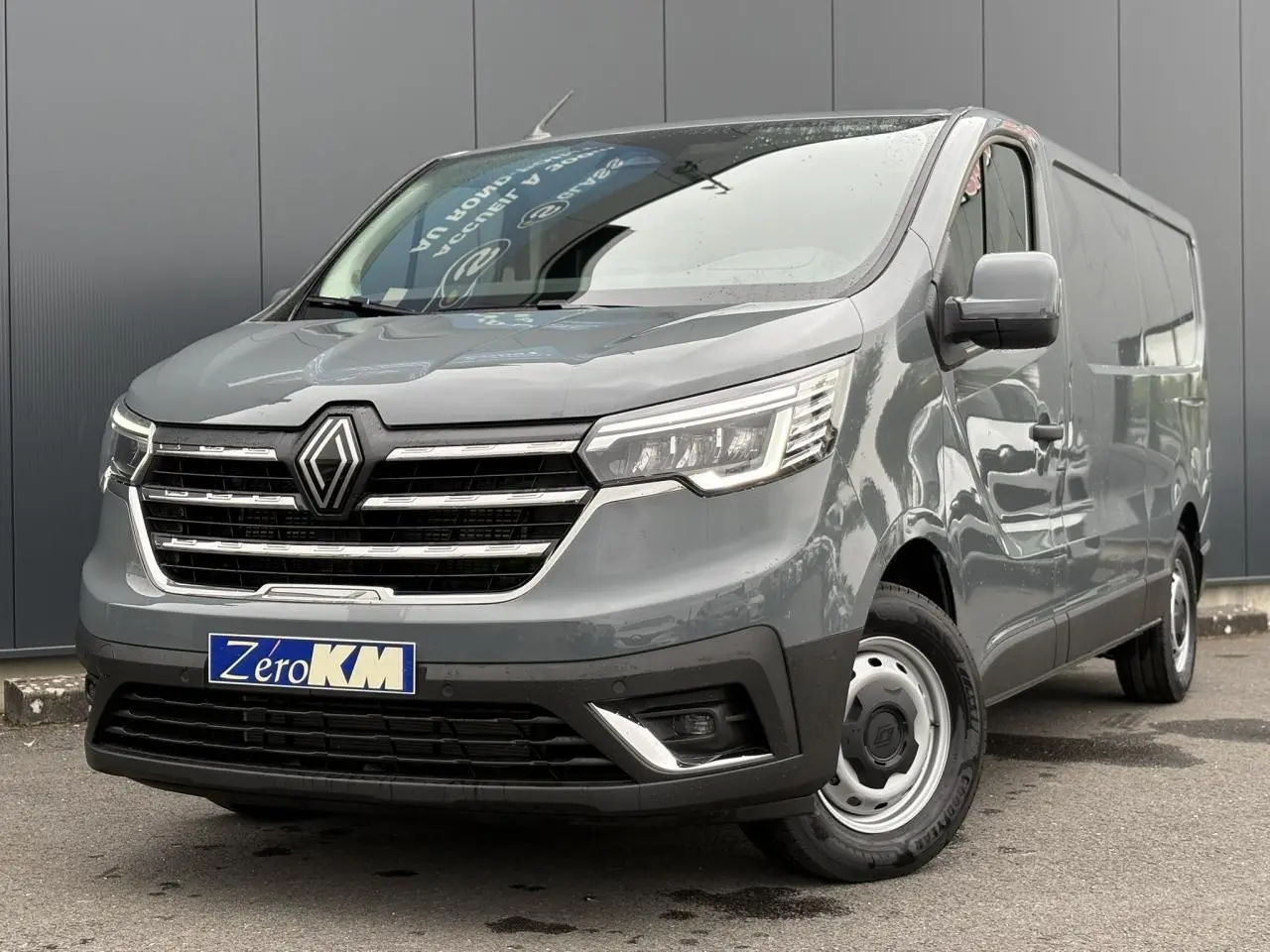 Fourgon Renault Trafic L2H1 gris urbain vu en 3/4 avant droit, avec calandre chromée et jantes acier simples.