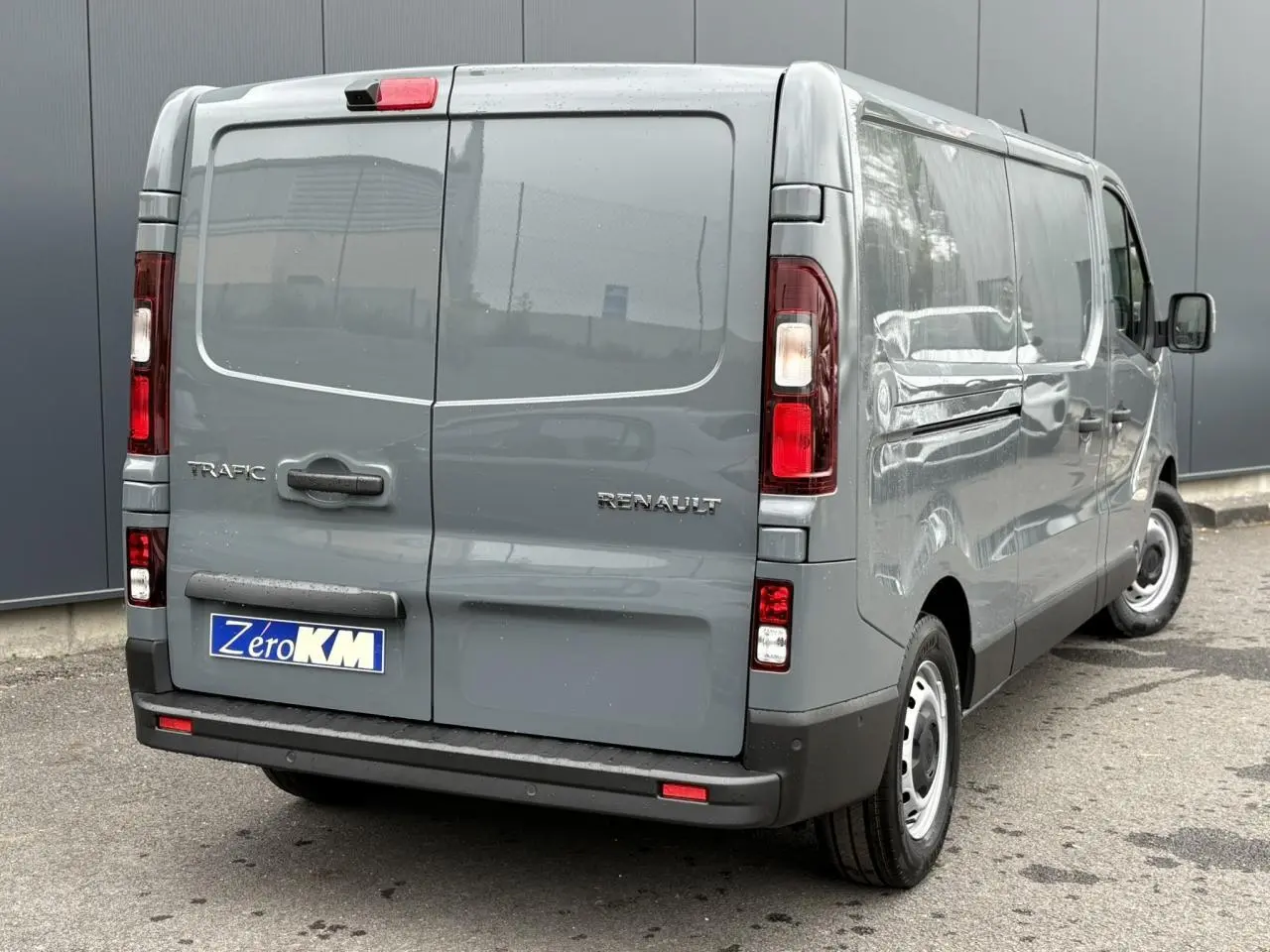Vue 3/4 arrière droite du fourgon Renault Trafic L2H1 2025 en gris urbain avec porte arrière fermée et jantes acier.