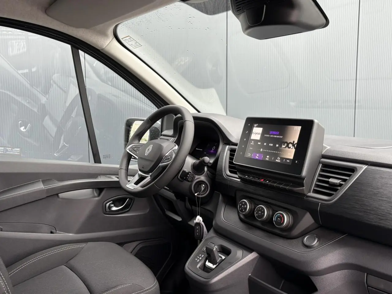 Vue intérieure côté conducteur du Renault Trafic Fourgon 2025, tableau de bord moderne avec écran tactile et volant cuir multifonction.