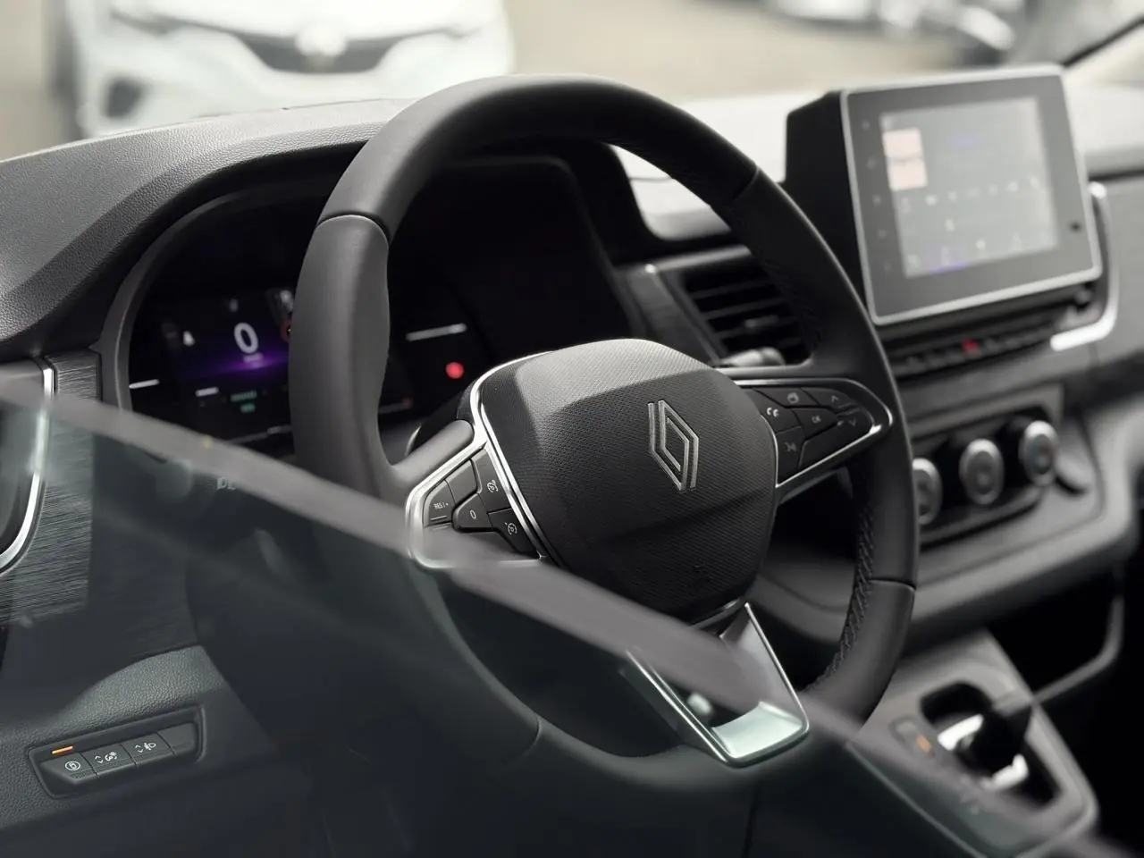 Vue intérieure centrée sur le volant en cuir multifonction du Renault Trafic Fourgon 2025 avec tableau de bord numérique.