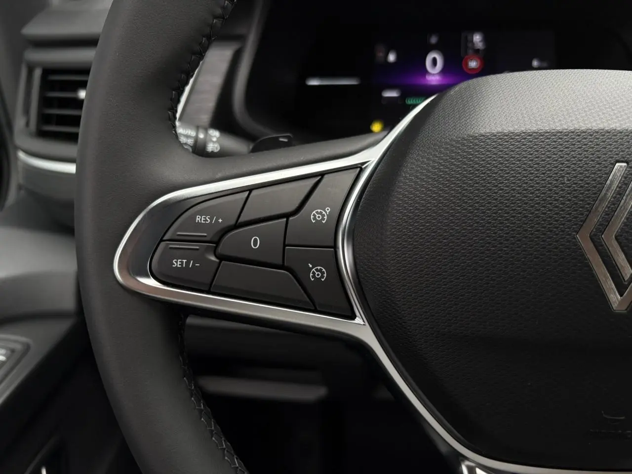 Gros plan sur le volant multifonction noir du Renault Trafic Fourgon 2025 avec commandes de régulateur de vitesse.