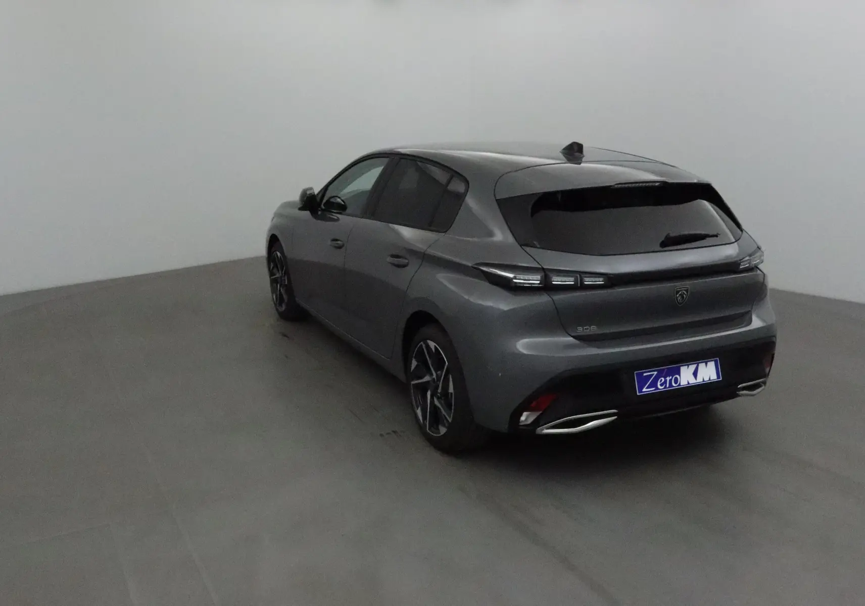 Vue 3/4 arrière droite d'une Peugeot 308 2025 gris Sellenium avec feux LED et double sorties d'échappement chromées.