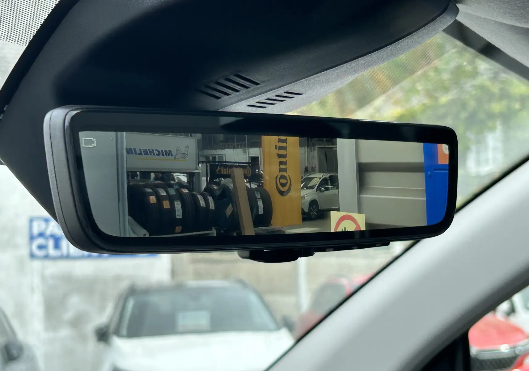 Rétroviseur intérieur numérique du Citroën Jumpy gris titane, affichant une vue arrière de pneus et véhicules en atelier.