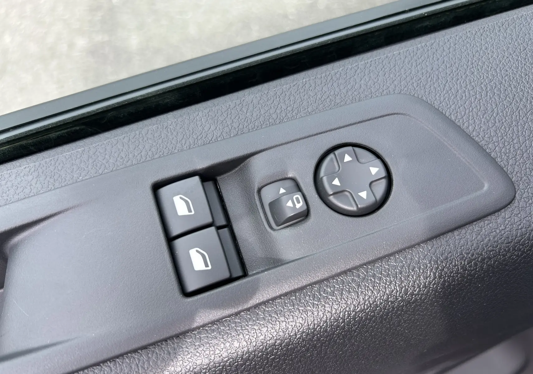 Commande des rétroviseurs et vitres électriques sur la portière côté conducteur d'un Citroën Jumpy gris titane 2025.