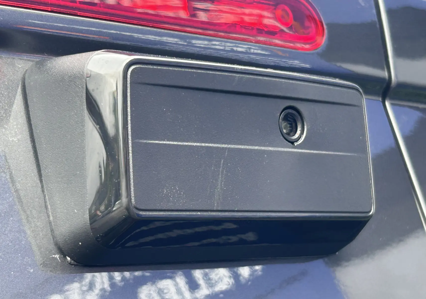 Gros plan sur la caméra de recul noire intégrée à la porte arrière d’un Citroën Jumpy gris titane.