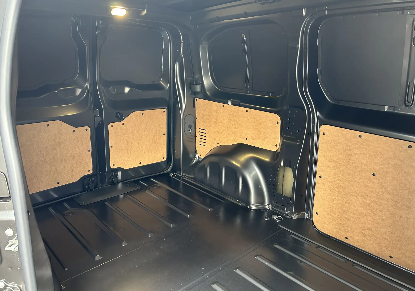 Intérieur du coffre du Citroën Jumpy gris titane, vue latérale montrant les panneaux de protection en bois clair.