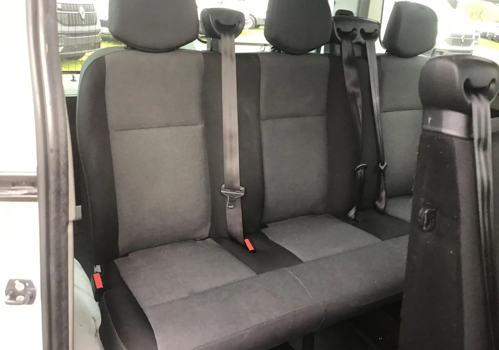 Vue intérieure montrant la banquette arrière gris foncé du Renault Master Combi III blanc, avec ceintures de sécurité visibles.