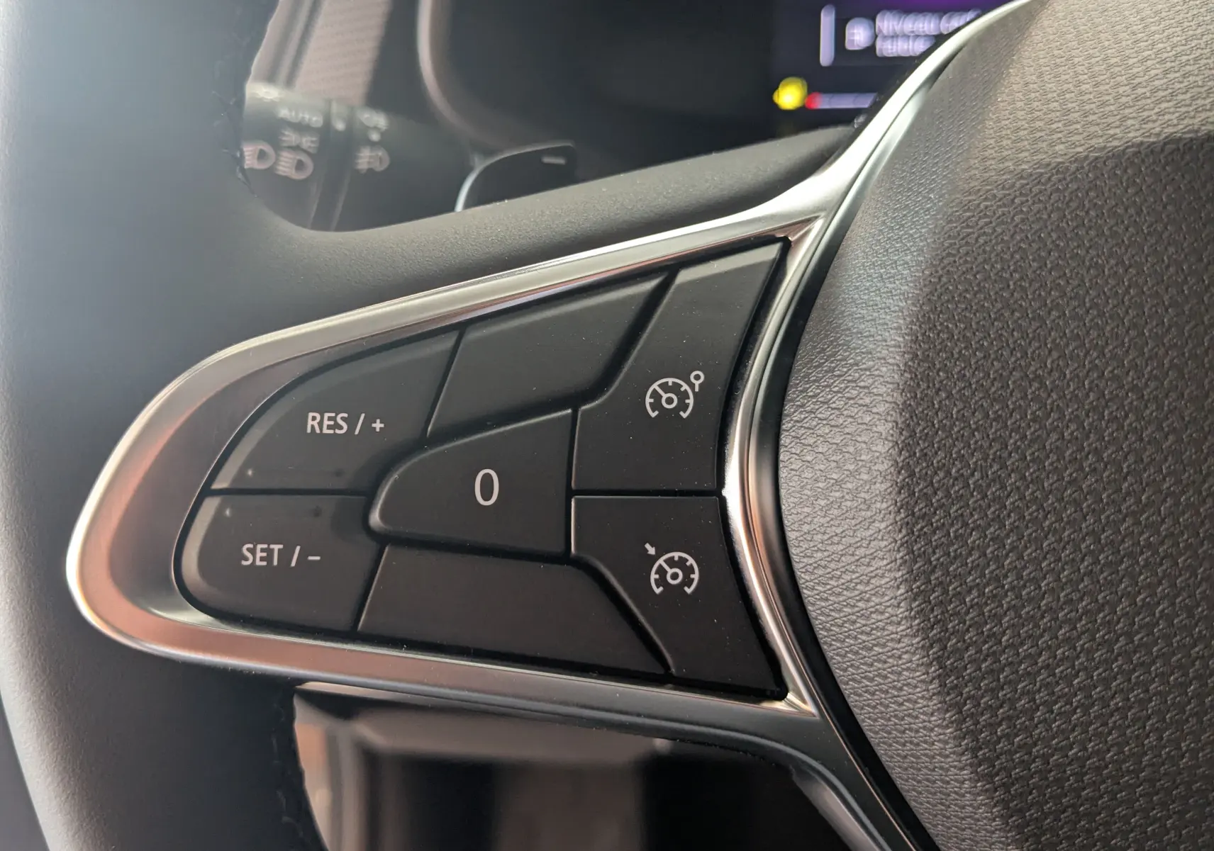 Gros plan sur les commandes de régulateur de vitesse au volant du Renault Trafic Cabine Approfondie gris Comète, côté gauche.