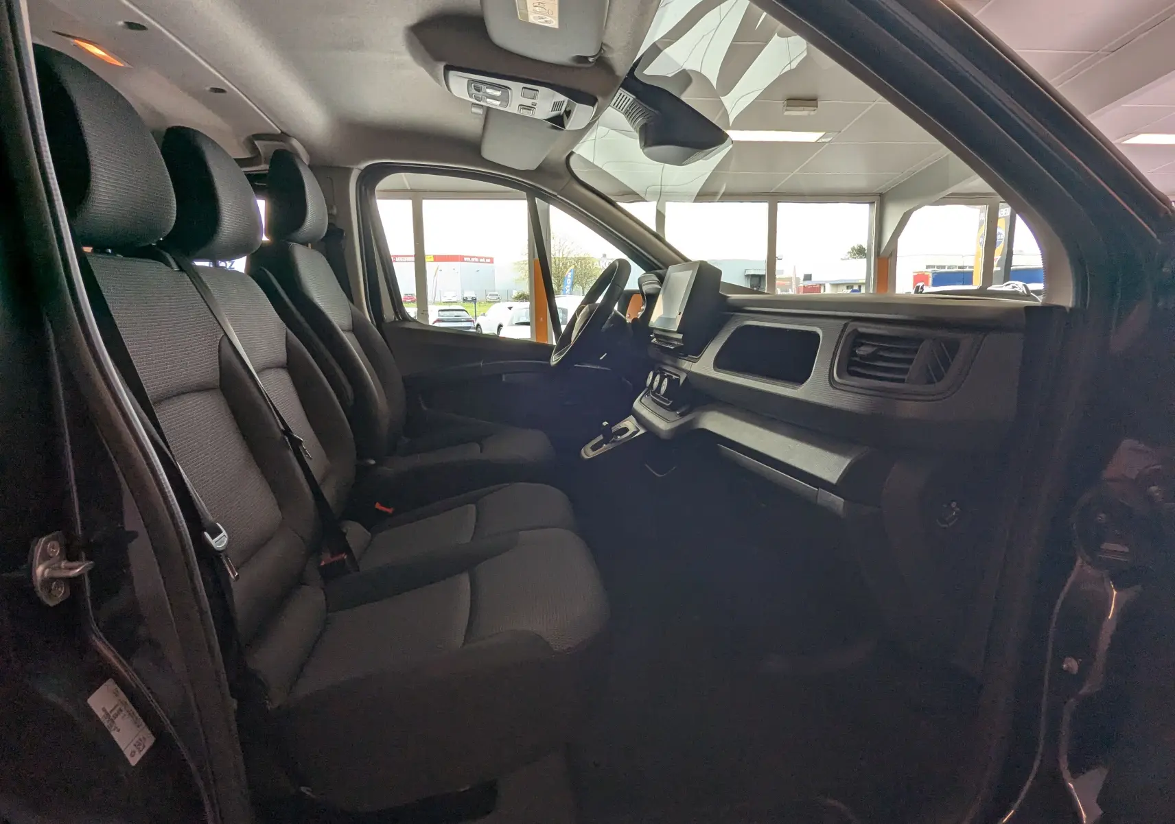 Vue intérieure côté conducteur du Renault Trafic Cabine Approfondie gris comète, montrant les sièges avant et le tableau de bord moderne.