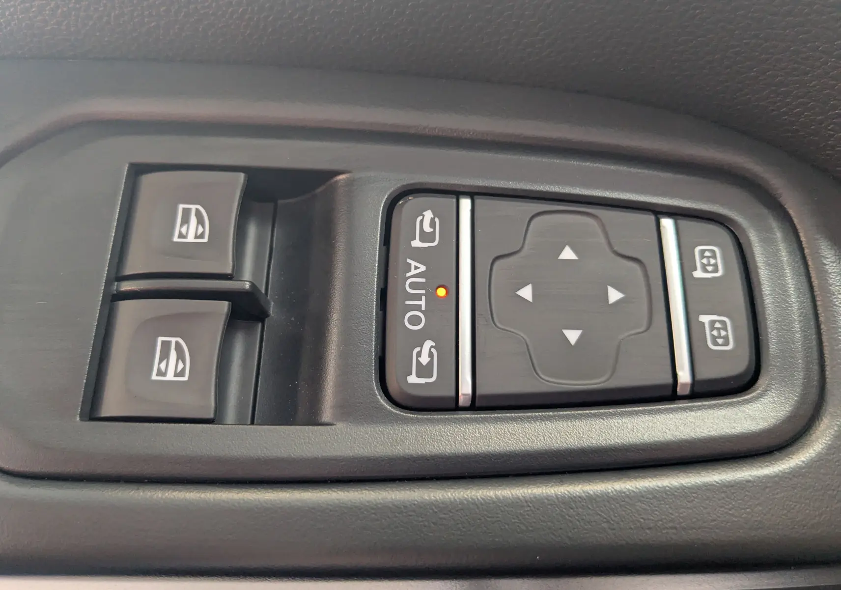 Gros plan sur les commandes de réglage des rétroviseurs et des vitres électriques côté conducteur du Renault Trafic gris comète.