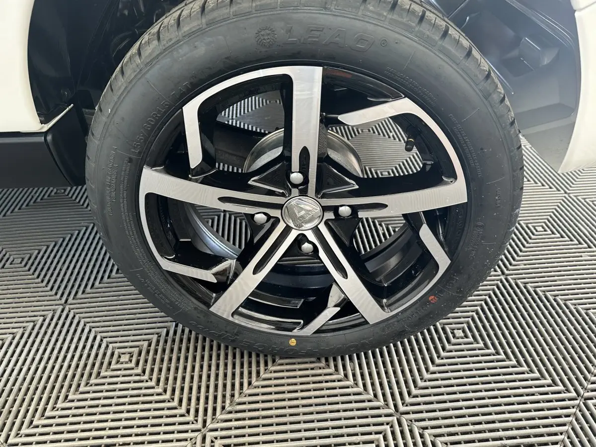 Gros plan sur la roue avant droite de l'AIXAM AMBITION 0.5 CROSSOVER PREMIUM blanche avec jante noire et argentée.