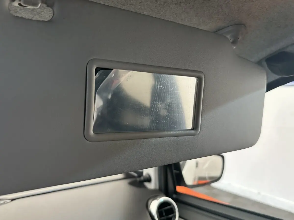 Miroir de courtoisie sur pare-soleil côté conducteur dans l’habitacle d’une Aixam Ambition blanc, vue intérieure rapprochée.
