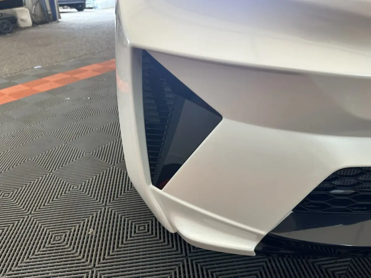 Gros plan sur l’angle avant gauche blanc de l’AIXAM AMBITION 0.5 CROSSOVER PREMIUM avec détail noir triangulaire.