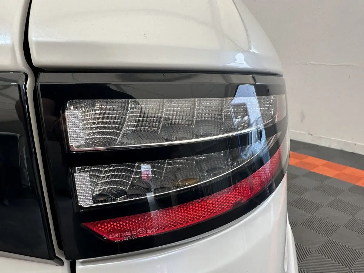 Gros plan sur le feu arrière droit du Aixam Ambition 0.5 Crossover Premium blanc, avec détails noirs et rouges.