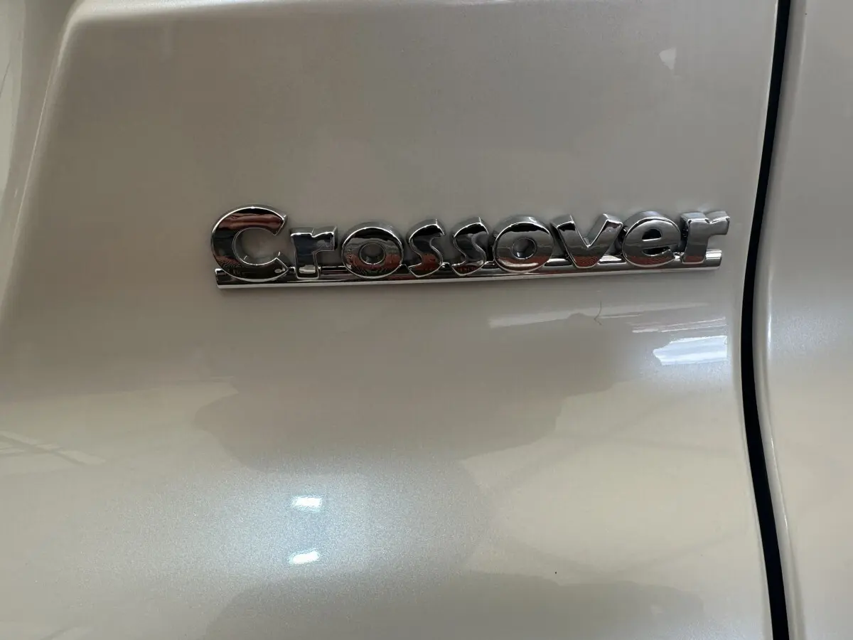 Gros plan sur l’inscription chromée "Crossover" sur la porte blanche d’une Aixam Ambition 0.5 Crossover Premium.