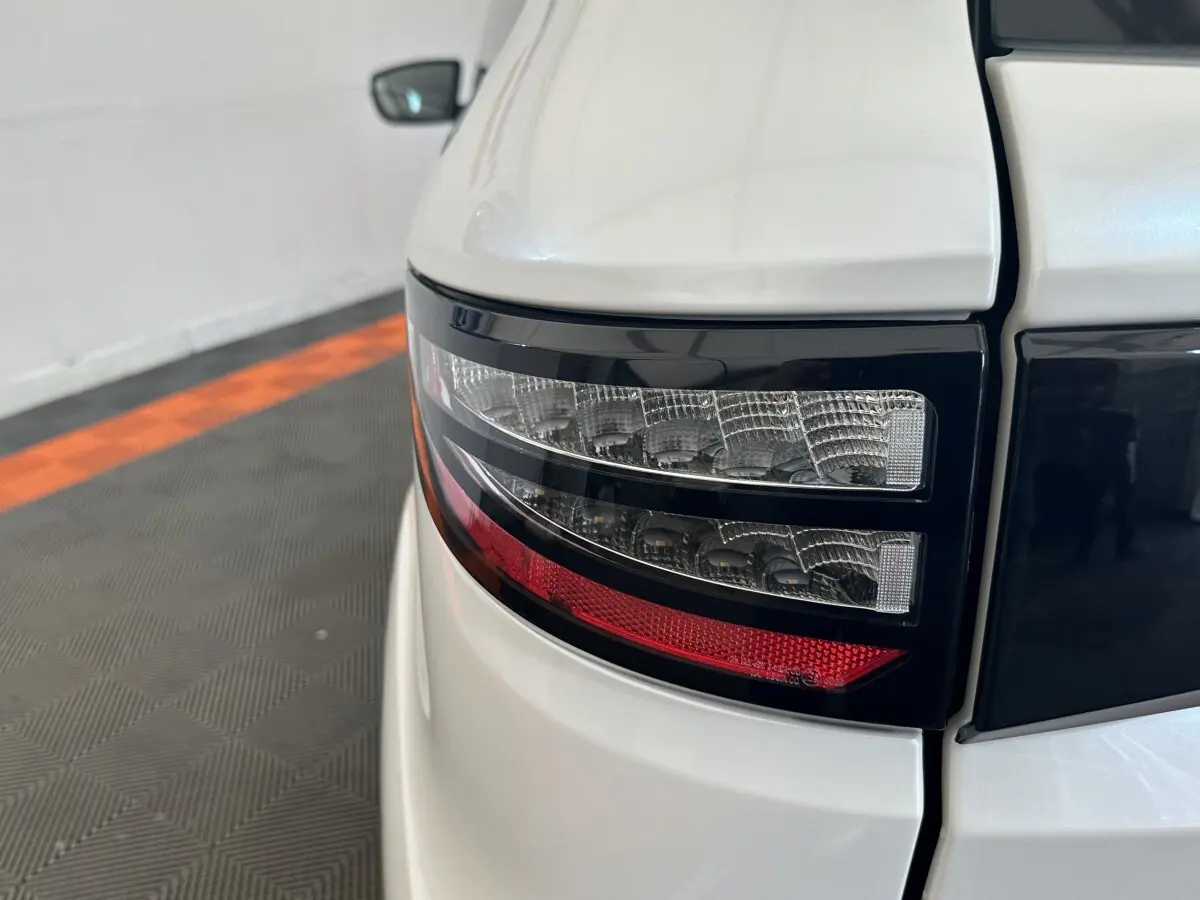 Gros plan sur le feu arrière droit noir et rouge d'une Aixam Ambition 0.5 Crossover Premium blanche, 2026.