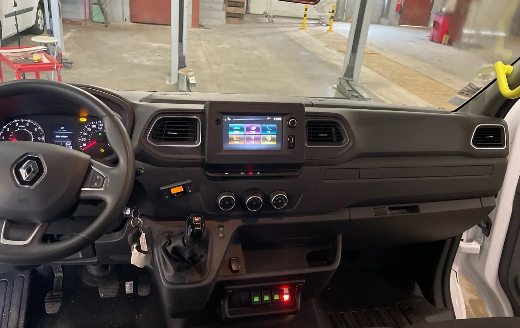 Vue intérieure du tableau de bord du Renault Master blanc, montrant le volant, la boîte manuelle et l’écran tactile central.