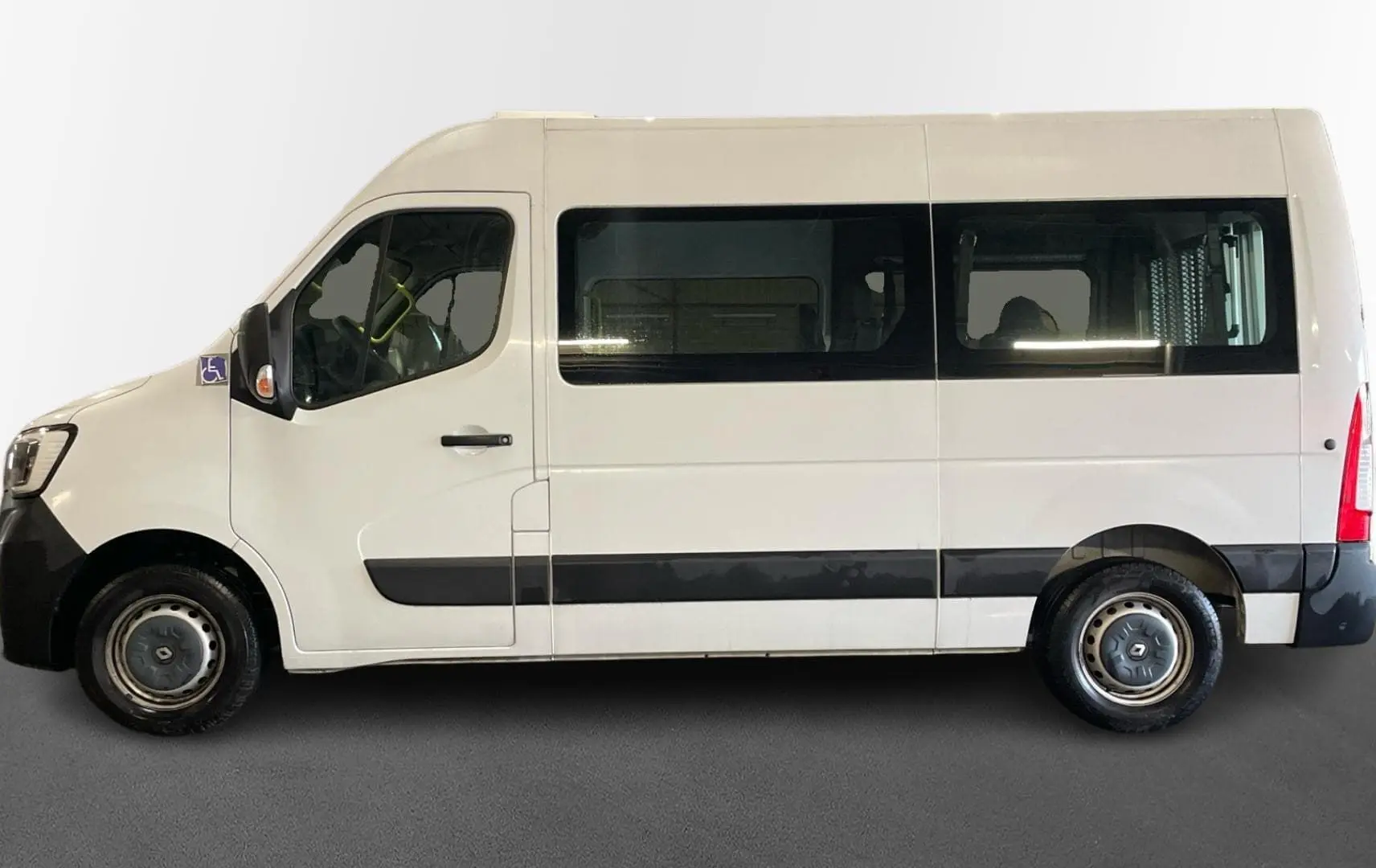 Profil gauche d’un Renault Master blanc TPMR 2020 avec grandes fenêtres latérales et rampe arrière visible.