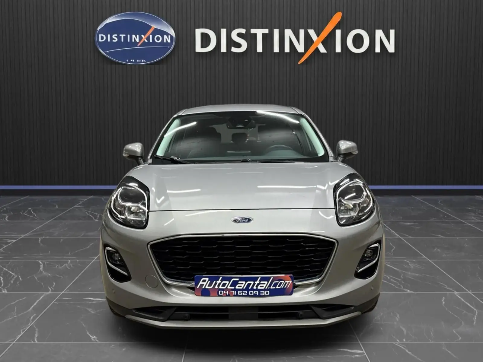 Vue frontale d'un Ford Puma gris solar 2023 avec calandre noire et phares LED, en showroom Distinxion.