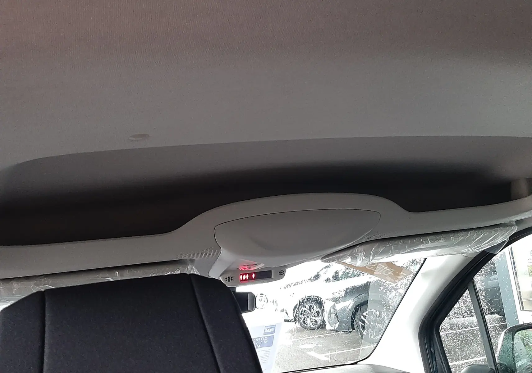 Vue intérieure avant droite du Citroën Berlingo 2026, montrant le plafond clair et le siège avant en tissu gris noir.
