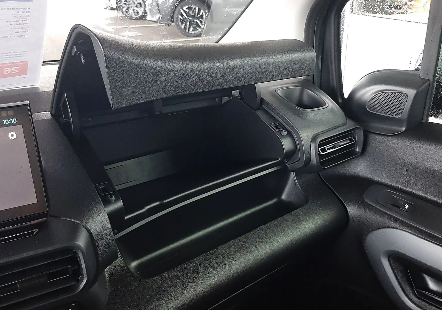 Vue intérieure côté passager du Citroën Berlingo 2026 bleu Kiama, avec boîte à gants ouverte et tableau de bord noir.