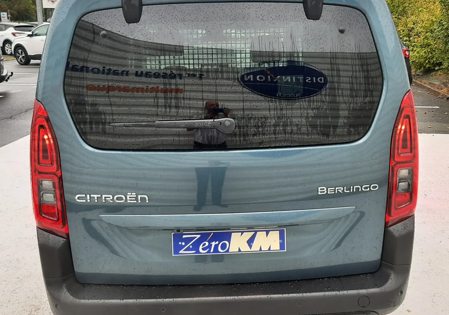 Vue arrière d'un Citroën Berlingo bleu Kiama 2026 avec hayon vitré et feux arrière allumés.