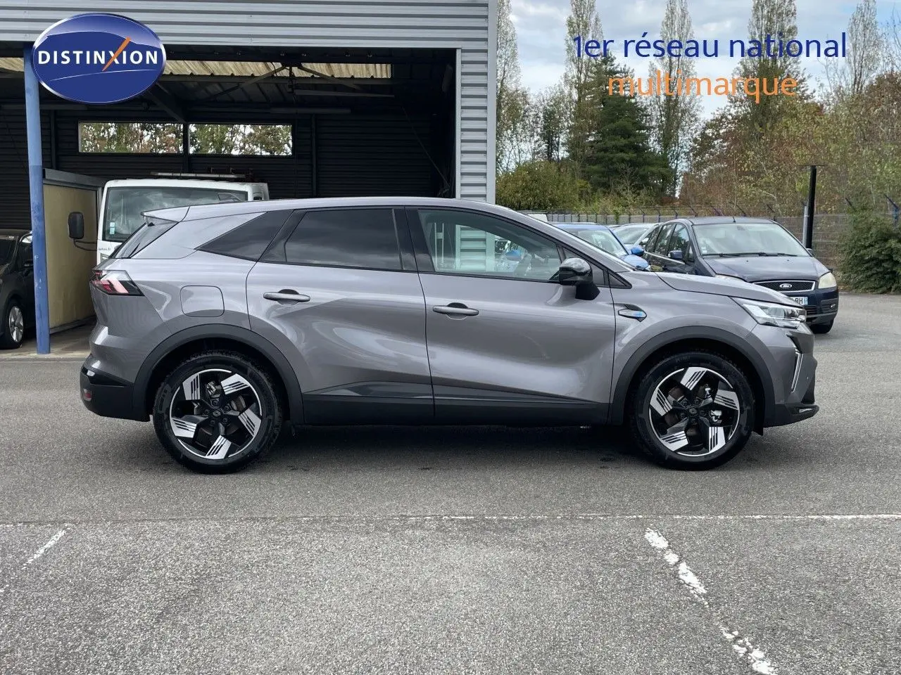 Vue latérale droite du Renault Symbioz gris cassiopée métal 2026, SUV hybride avec jantes stylisées bicolores.