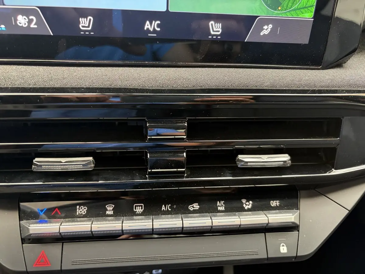Détail de la console centrale de la Renault Clio 2025 rouge, montrant les commandes de climatisation et les aérateurs noirs.