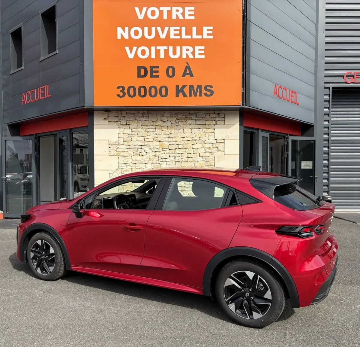 Renault Clio Evolution rouge vue de profil côté gauche, avec jantes noires et toit légèrement incliné.