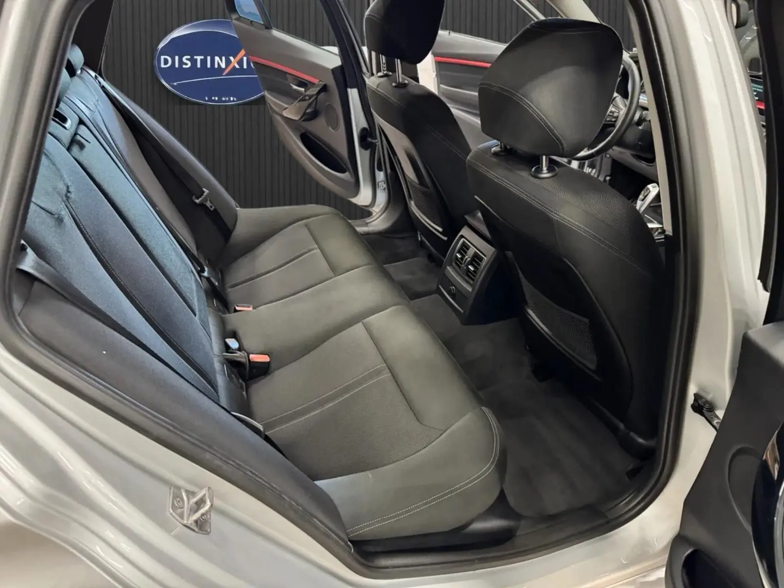 Vue intérieure côté arrière gauche de la BMW Série 3 Touring gris aluminium, montrant les sièges noirs et la porte ouverte.