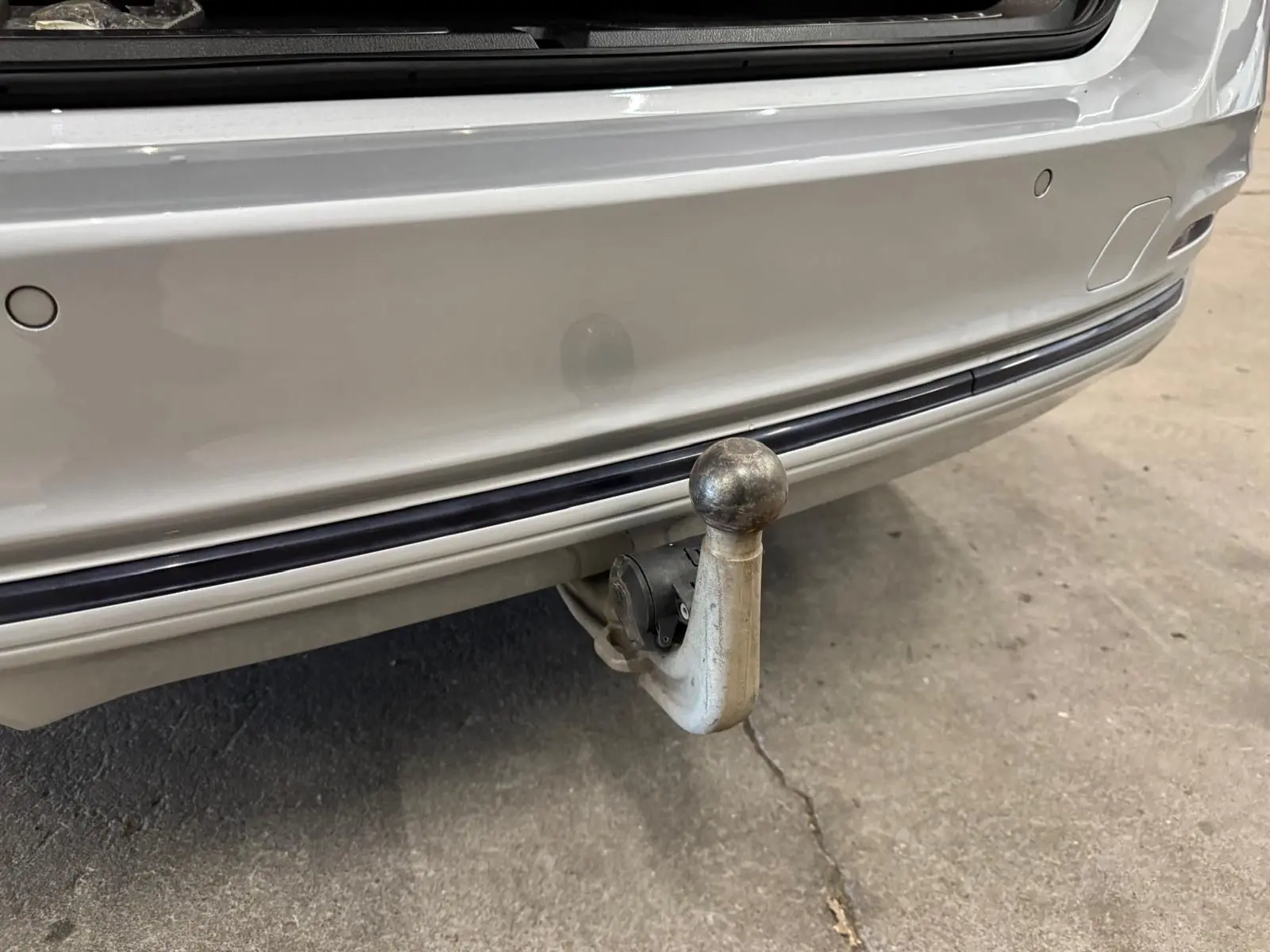 Gros plan sur l'attelage électrique arrière d'une BMW Série 3 Touring F31 gris aluminium, avec pare-chocs visible.