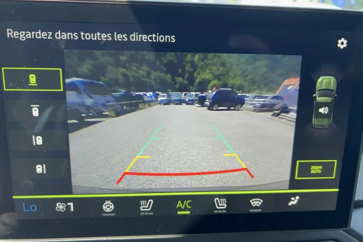 Vue écran caméra multiview du Dacia Duster vert cèdre 2026, affichant la zone arrière avec lignes de guidage colorées.