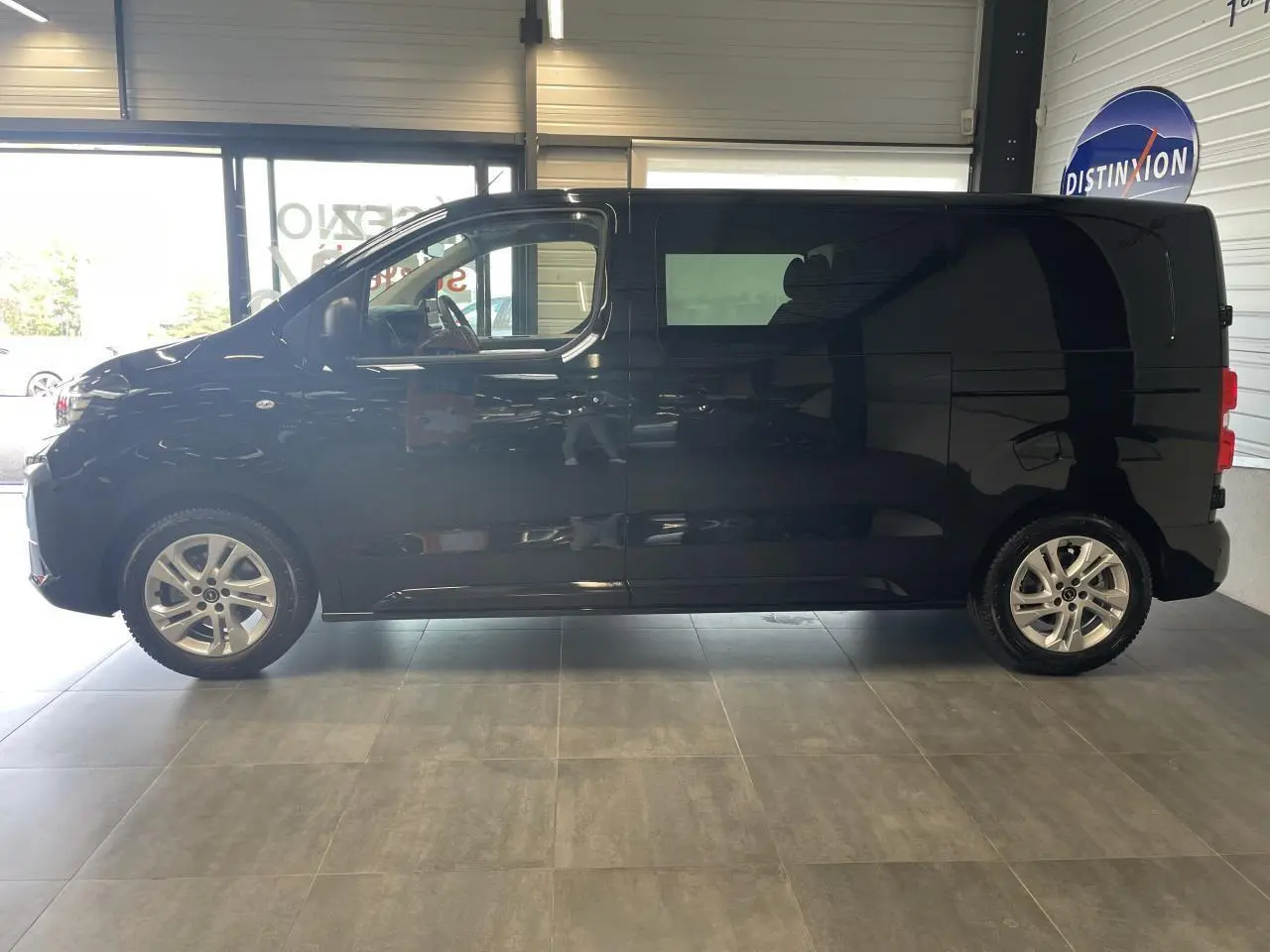 Profil latéral gauche du fourgon Opel Vivaro noir carbone, double cabine, roues alliage et vitres surteintées visibles.