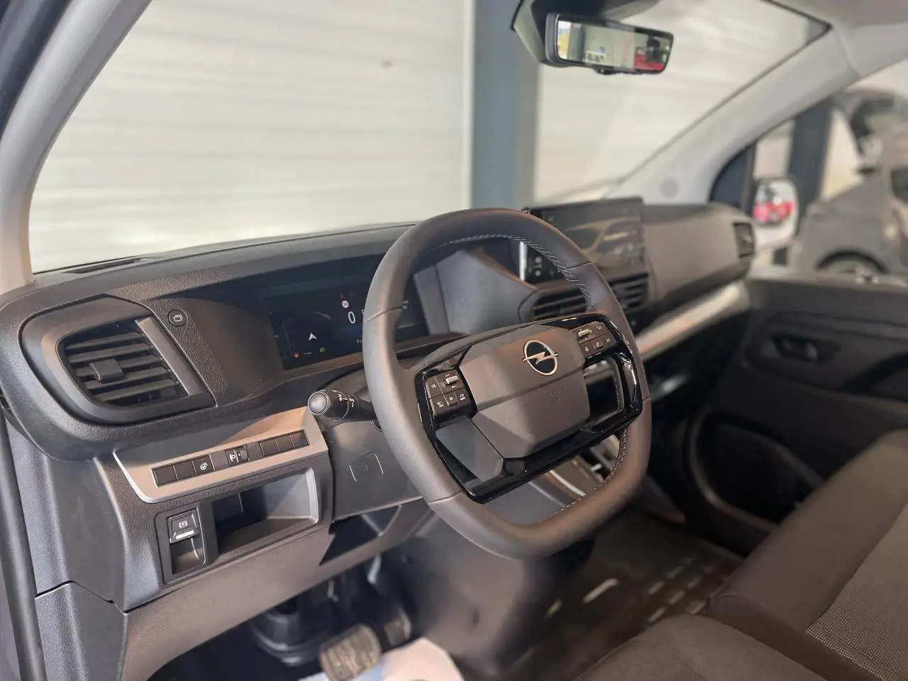 Intérieur de l'Opel Vivaro 2025 côté conducteur, volant multifonction et tableau de bord moderne noir.