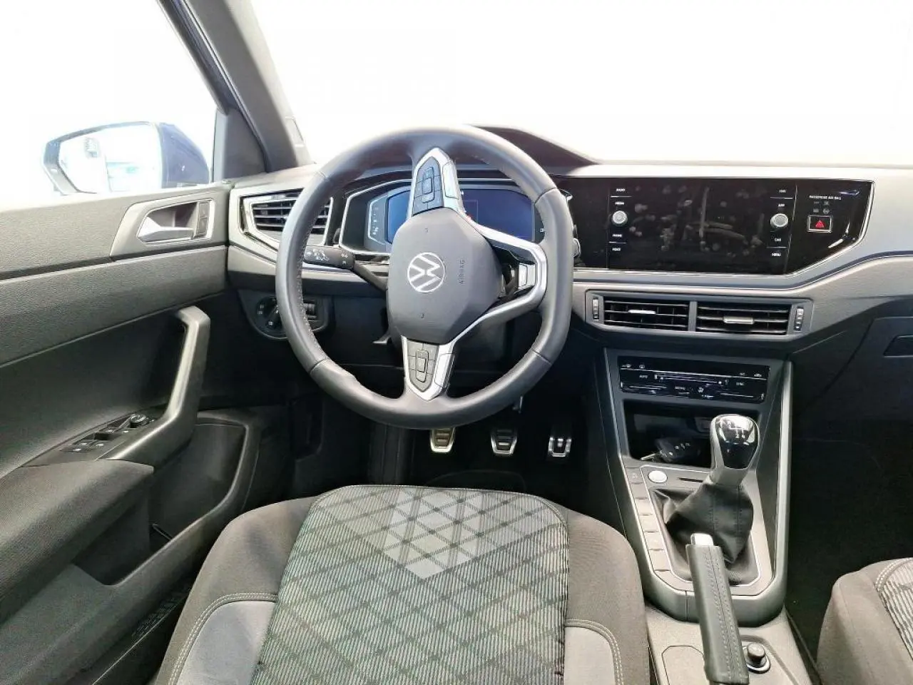 Vue intérieure frontale du poste de conduite de la Volkswagen Polo TSI 95 R-Line 2024 avec volant cuir multifonction et levier de vitesses manuel.
